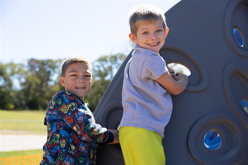 Two boys climb on playground equipment